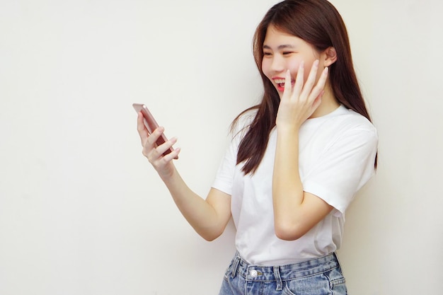 Fröhliche Frauen, die weiße T-Shirts tragen und ein Telefon halten