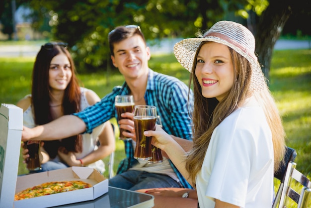 Fröhliche Freunde beim Picknick im Park. Pizza essen