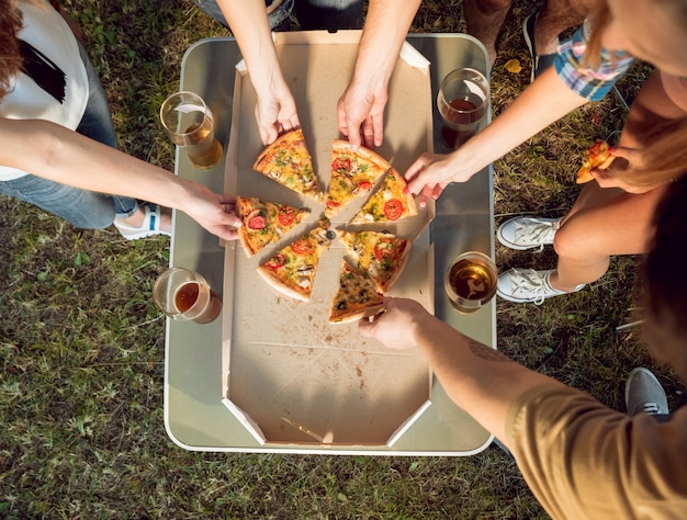 Fröhliche Freunde beim Picknick im Park. Pizza essen