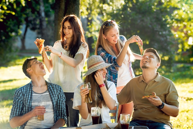 Fröhliche Freunde beim Picknick im Park. Pizza essen