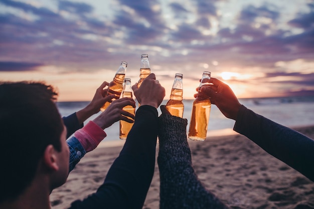 Fröhliche Freunde, die am Strand anstoßen