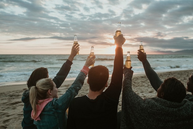 Fröhliche Freunde, die am Strand anstoßen