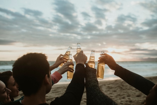 Fröhliche Freunde, die am Strand anstoßen