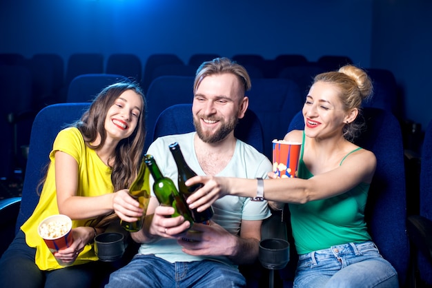 Fröhliche Freunde, die im Kino mit Flaschen klirren