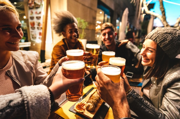 Fröhliche Freunde, die in der Nachtstimmung Bier in der Brauereibar trinken