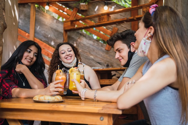 Fröhliche Freunde, die mit einem gesunden Orangensaft in einer Bar rösten.