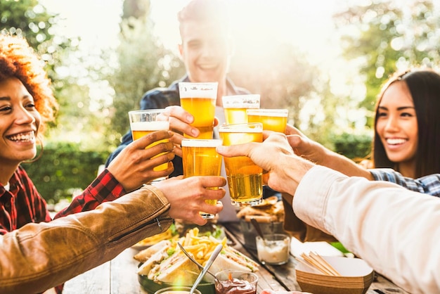 Fröhliche Freunde feiern Happy Hour beim Biertrinken im Brauerei-Bar-Restaurant - Multiethnische Familie, die Spaß bei der Dinnerparty im Hinterhof hat - Junge Leute, die gemeinsam Zeit im Open-Air-Pub genießen