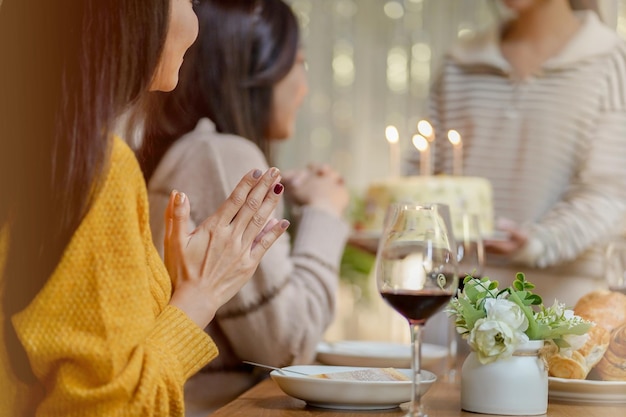 Foto fröhliche freunde genießen zu hause geburtstagsfeier asiatische schwester jubelt beim trinken von rotwein und feiert mit geburtstagstorte
