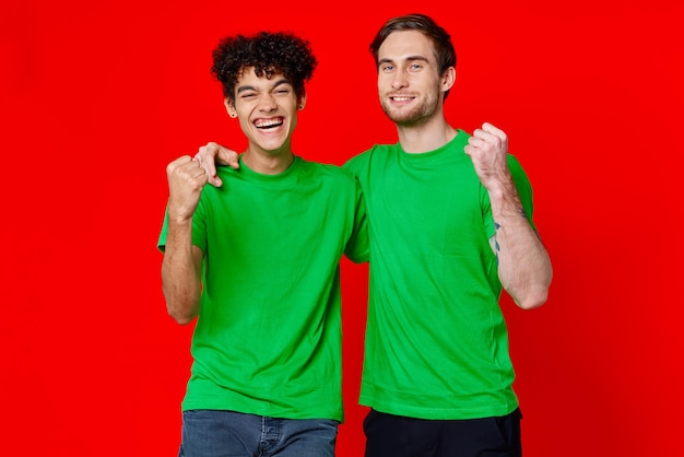 Fröhliche Freunde grüne T-Shirts Emotionen Kommunikation Umarmung Freundschaft