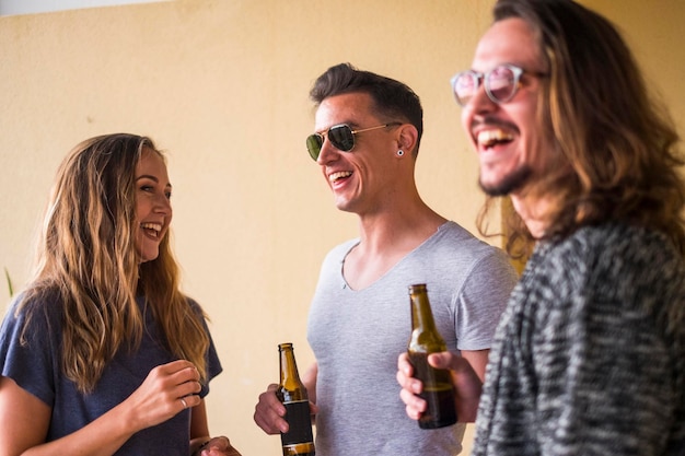 Fröhliche Freunde trinken Bier, während sie an der Wand stehen
