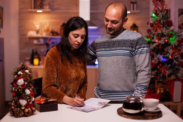 Fröhliche Freundin, die Weihnachtsgrußpostkarte schreibt, die Weihnachten Wintersaison feiert