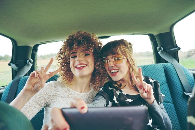 Foto fröhliche freundinnen machen ein selfie, während sie im auto sitzen