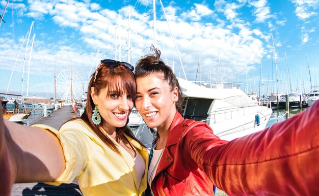 Fröhliche Freundinnen machen lustige Selfies an Segelboot-Docks