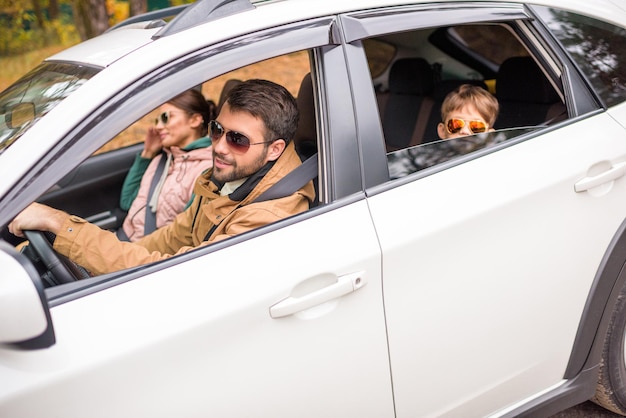 Fröhliche, freundliche Familie, die mit dem Auto auf der Landstraße unterwegs ist