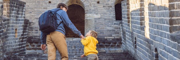 Fröhliche, fröhliche Touristen, Vater und Sohn an der Chinesischen Mauer, die Spaß auf der Reise haben und lächeln