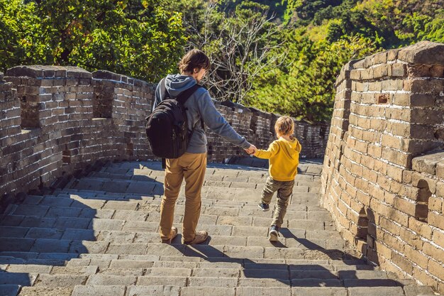 Fröhliche, fröhliche Touristen, Vater und Sohn an der Chinesischen Mauer, die Spaß auf der Reise haben und lächeln