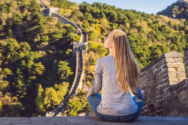 Fröhliche, fröhliche Touristenfrau an der Chinesischen Mauer meditiert auf Urlaubsreise in Asien Mädchen