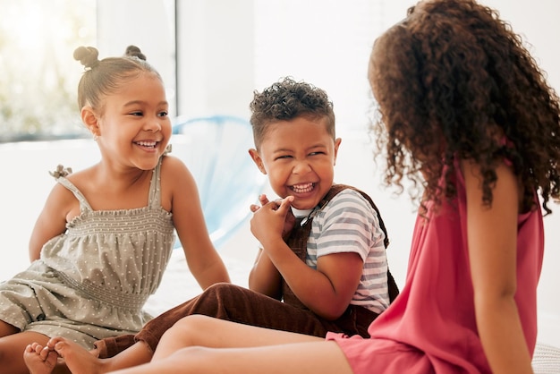 Fröhliche, fröhliche und lachende Kinder, die zusammensitzen und Spaß bei einem Playdate haben Entzückende Jungen und Mädchen, die ihre gemeinsame Zeit zu Hause genießen Geschwister, Schwestern und Bruder, die sich verbinden und spielen