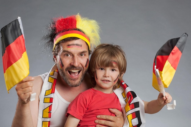 Foto fröhliche fußballfans mit deutschen fahnen auf grauem hintergrund