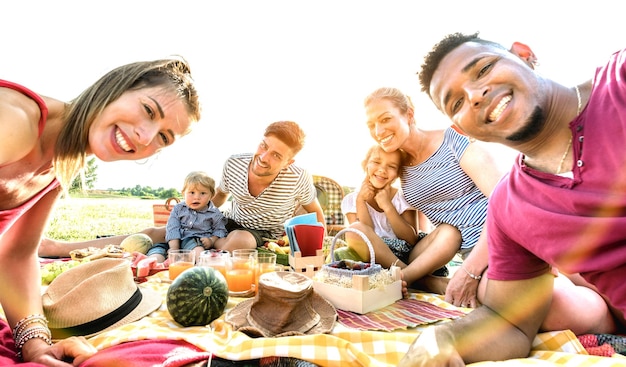 Fröhliche gemischtrassige Familien, die sich auf einer Pic-Nic-Gartenparty selbst machen