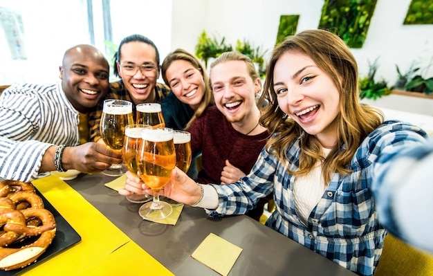 Fröhliche gemischtrassige Freunde, die Bier in der Brauereikneipe trinken