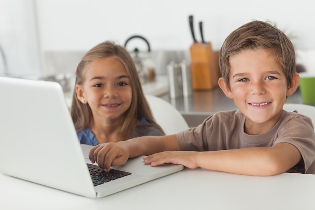 Fröhliche Geschwister, die zusammen einen Laptop verwenden