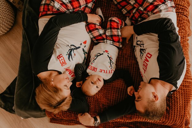 Fröhliche glückliche Familie im Schlafanzug mit Kind liegen auf dem Bett im Schlafzimmer. Neujahr Familienkleidung sieht Outfits. Valentinstag Feier Geschenke