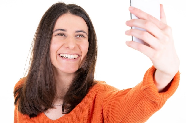 Fröhliche glückliche Frau, die Handy hält und lächelt, die selfie auf weißem Hintergrund isoliert macht