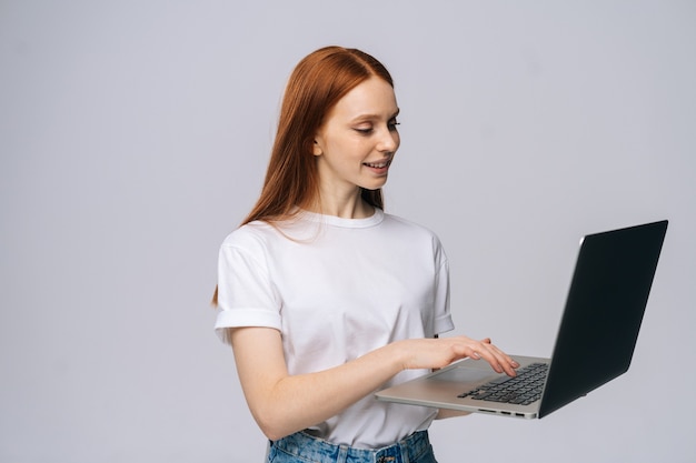 Fröhliche glückliche junge Geschäftsfrau oder Studentin, die Laptop-Computer hält und wegschaut