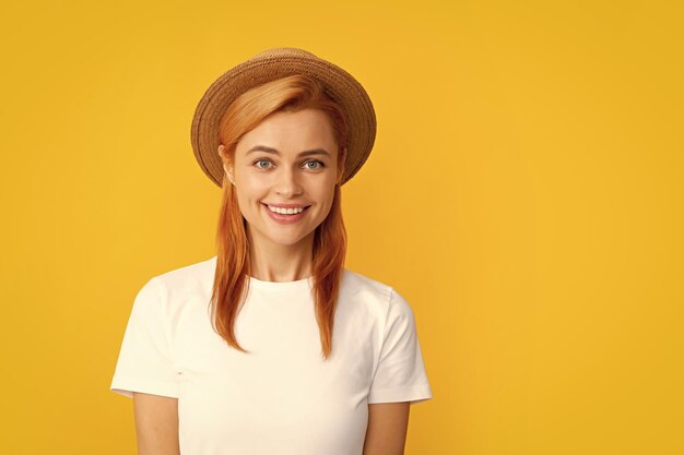 Fröhliche, glückliche, stilvolle Frau, die mit Strohhut im Studio auf gelbem Hintergrund posiert Sommermädchenporträt