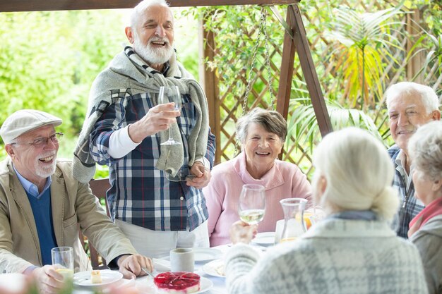 Foto fröhliche gruppe pensionierter freunde, die sich während der geburtstagsfeier im garten amüsieren