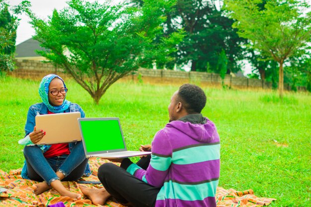 Fröhliche gute afrikanische Freunde, die sich mit dem Smartphone im Freien amüsieren - Freundschaftskonzept mit Jungen und Mädchen bei Spring Break Reisen - moderner männlicher und weiblicher Lebensstil