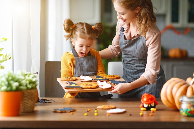 Fröhliche Halloween-Familienmutter und Tochter bereiten sich auf den Urlaub vor und backen Kekse