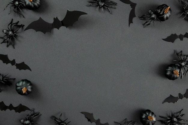 Fröhliche Halloween-Flachkomposition mit schwarzen Kürbissen, Spinnen und Fledermäusen auf dunklem Hintergrund. Urlaubskonzept. Ansicht von oben. Platz kopieren.