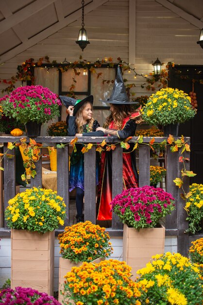 fröhliche Halloween-Mädchen in Hexenkostümen haben Spaß im Herbst in der Nähe des Hauses