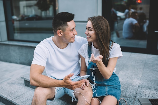 Fröhliche Hipster-Typen sitzen in einer Umgebung, die eine Verbindung zum öffentlichen Internet herstellt, um Sprachnachrichten zu hören