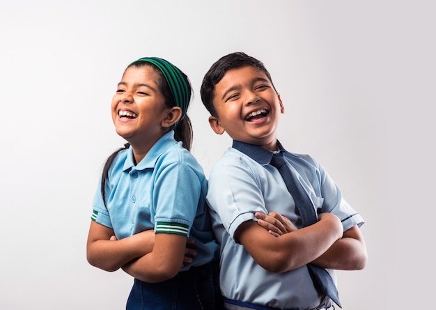 Fröhliche indische Schulkinder in Uniform stehen isoliert auf weißem Hintergrund
