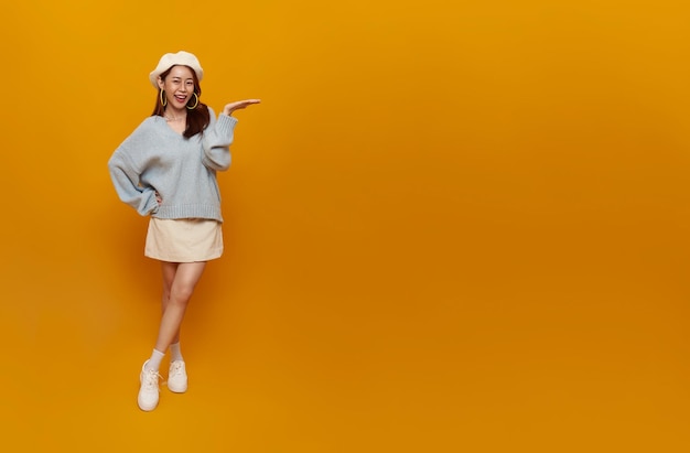 Fröhliche junge asiatische Teenie-Frau, die offene Handfläche mit Kopierraum für Produkt präsentiert oder zeigt