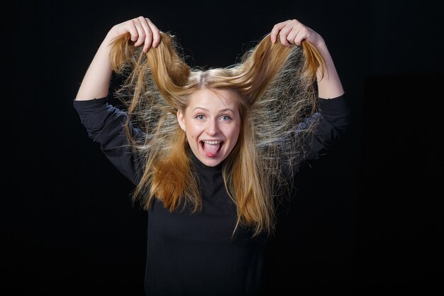 Foto fröhliche junge blonde frau lacht auf einem schwarzen hintergrundsad junges mädchen blondes haar, das horizontalen rahmen weint