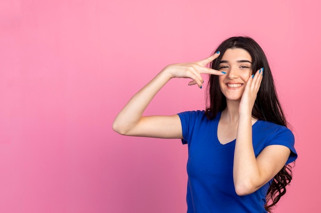 Fröhliche junge Dame gestikuliert Frieden und lächelt Hochwertiges Foto