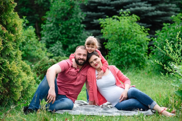 Fröhliche junge Familie, die draußen in der grünen Natur Zeit miteinander verbringt