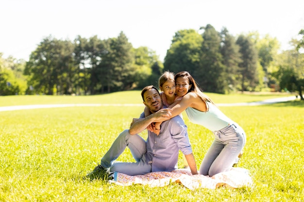 Fröhliche junge Familie mit süßer kleiner Tochter, die sich an einem sonnigen Tag im Park amüsiert