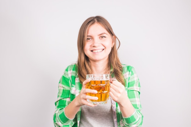 Fröhliche junge Frau, die einen Bierkrug voller Bier hält und auf weißem Hintergrund lächelt.