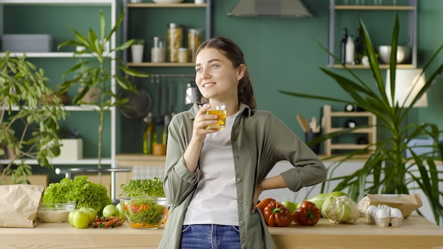 Fröhliche junge Frau, die frisch gepressten Saft mit Bio-Produkten genießt