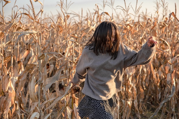 Fröhliche junge Frau in einem Maisfeld im Herbst.