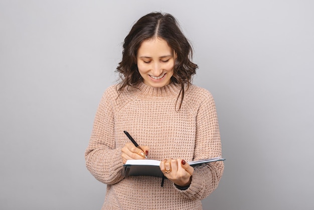 Fröhliche junge Frau schreibt im Journal Studioaufnahme