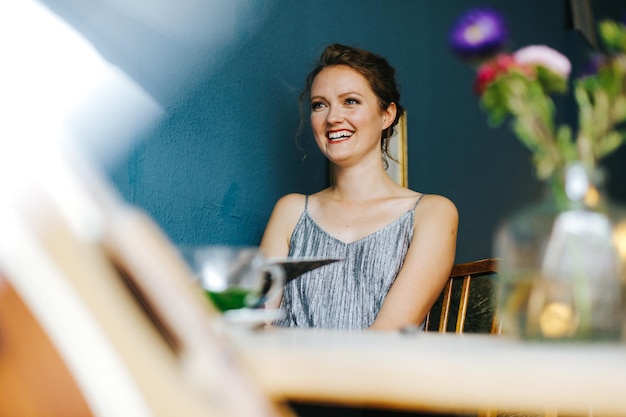 Fröhliche junge Frau sieht ab, während sie im Café sitzt