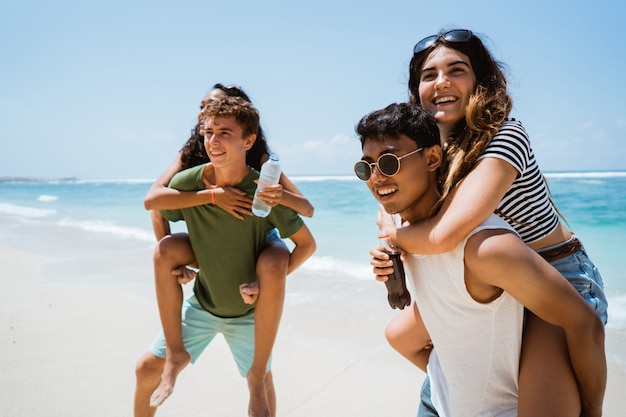 Fröhliche junge Freunde, die Sommerzeit am Strand genießen