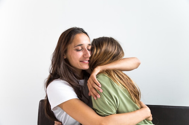 Fröhliche junge Freunde umarmen sich, während sie zu Hause sitzen