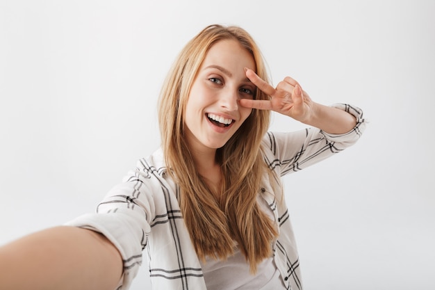 Fröhliche junge lässige Frau, die selfie nimmt